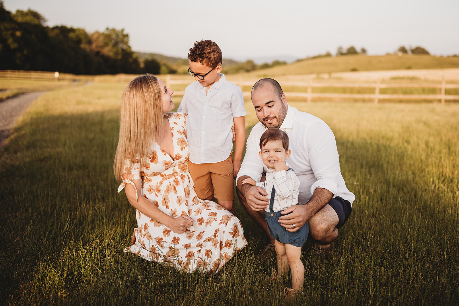 A family of four play together in a pasture at sunset