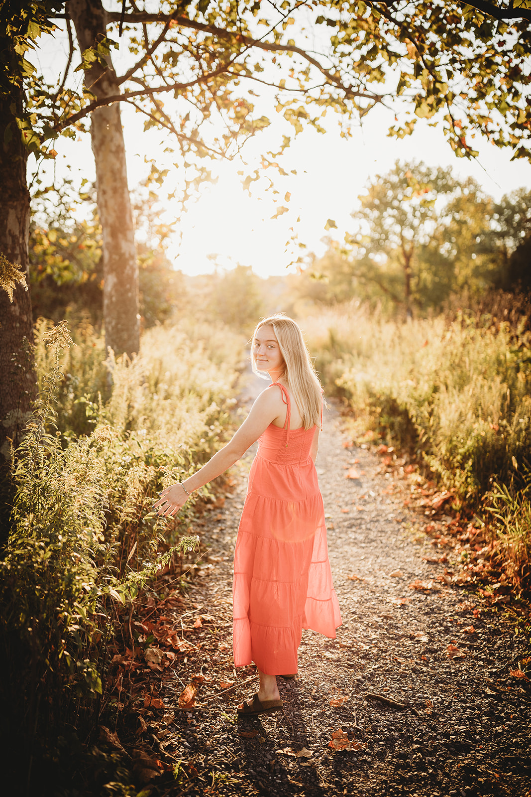 A teen girl in a pink dress explores a trail at sunset after shopping for Prom Dresses Harrisonburg, VA