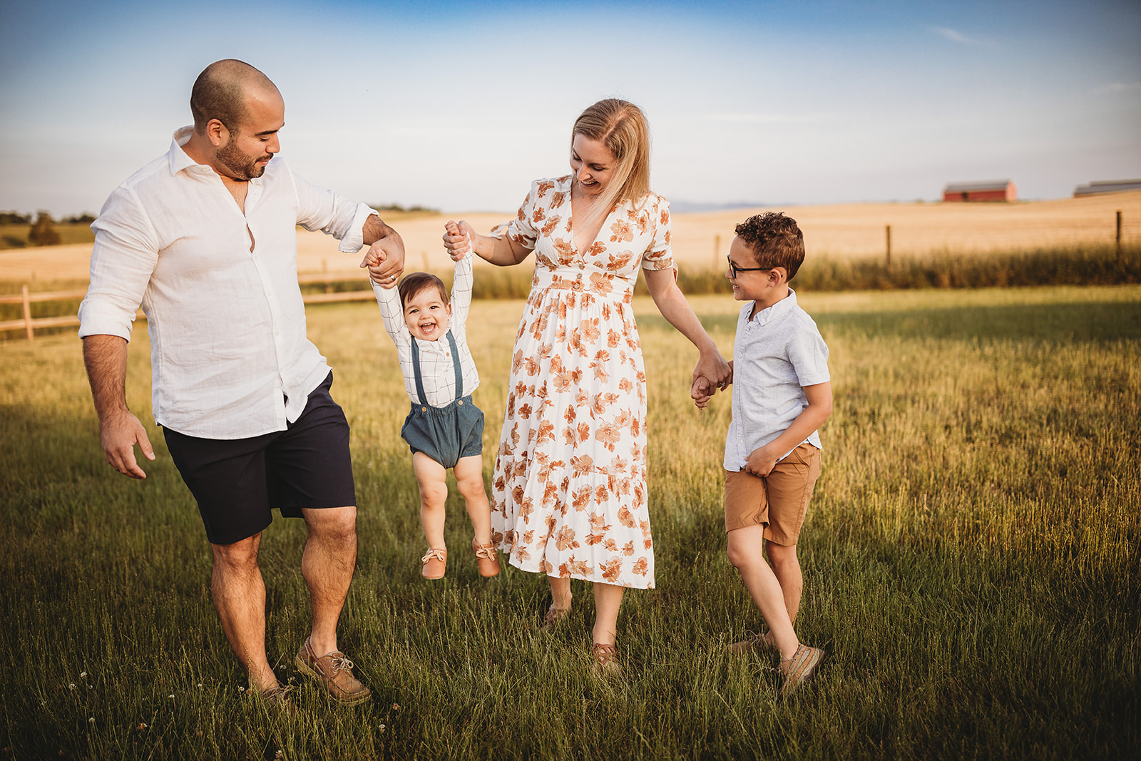 A happy family plays and laughs in a pasture while holding hands