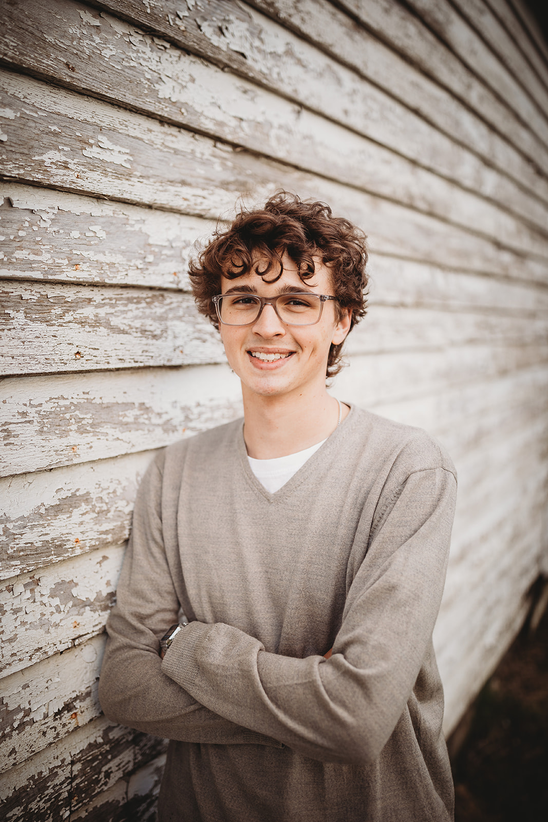 A high school senior smiles while leaning on a wall in a grey shirt before finding Volunteer Opportunities in Harrisonburg, VA