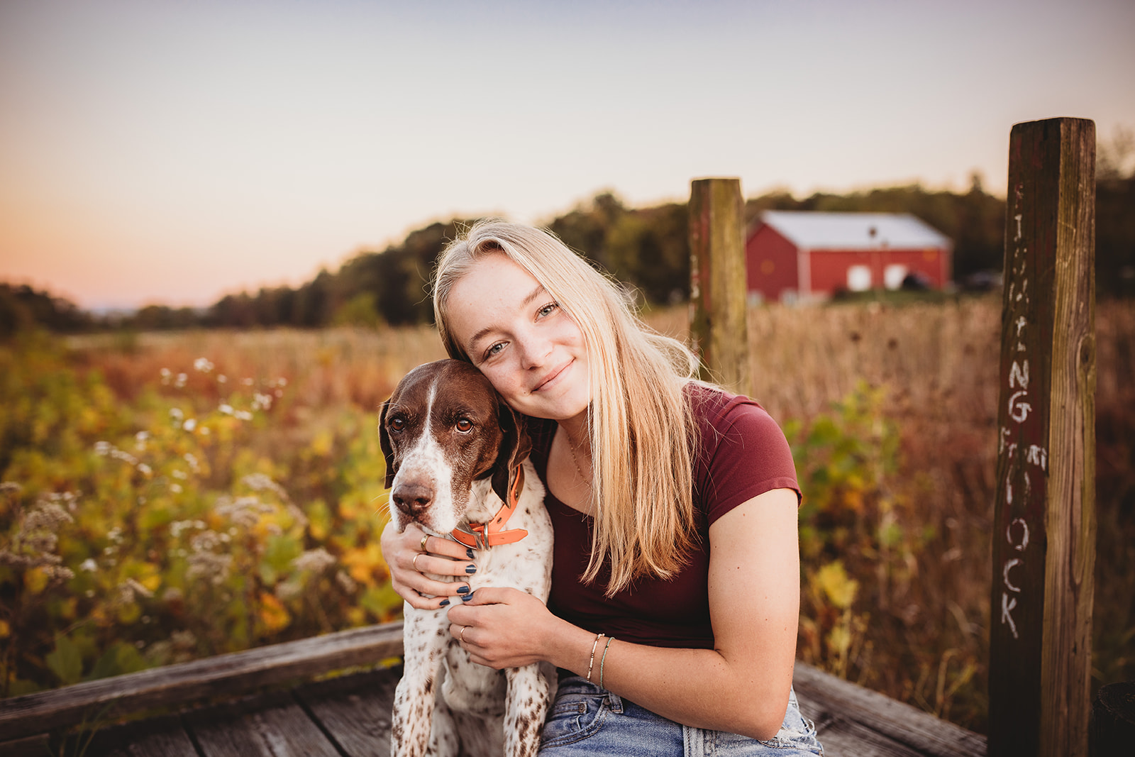 A happy girl sits on a dock hugging her dog at sunset after finding Volunteer Opportunities in Harrisonburg, VA